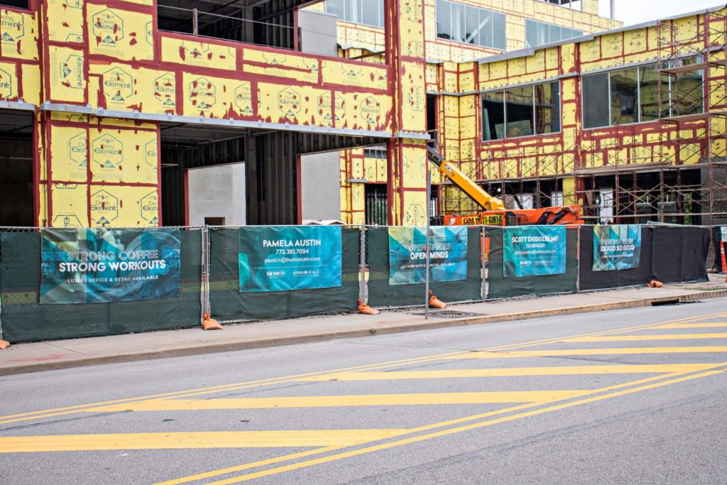 banners on fence in front of a building under construction
