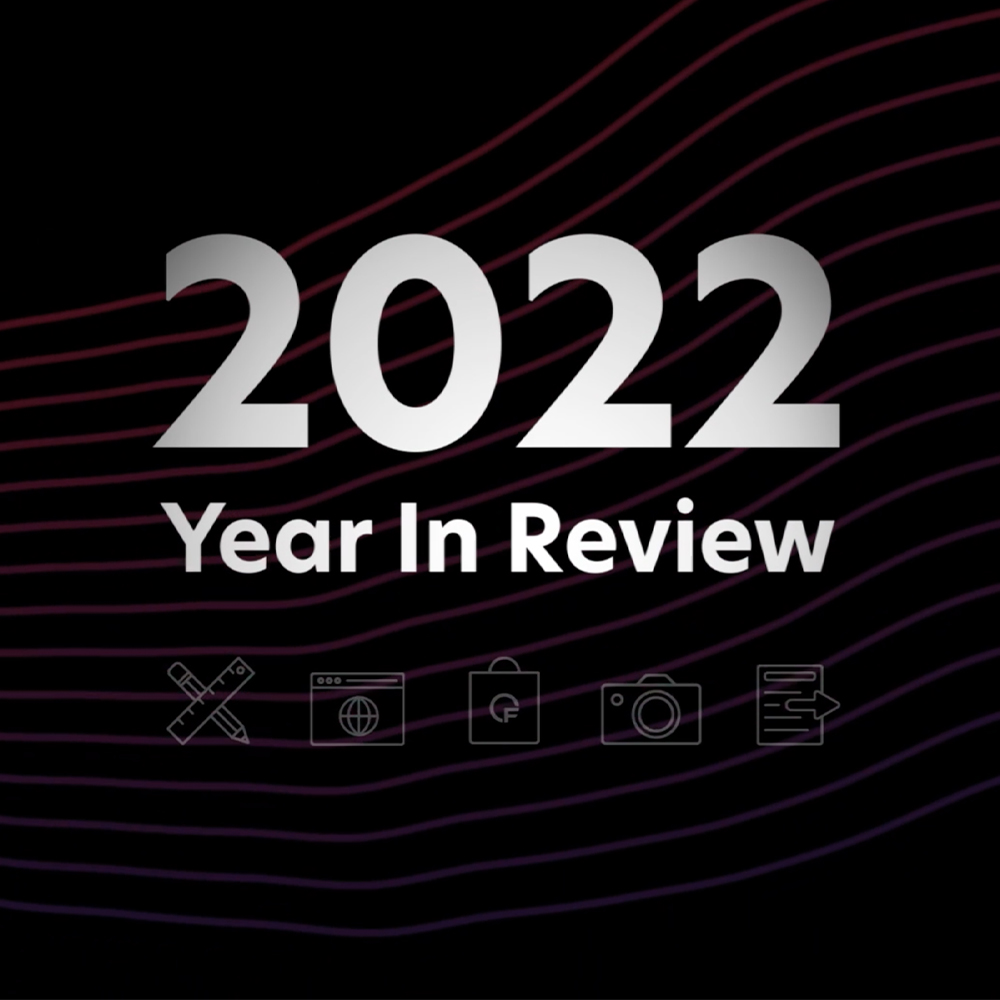 The image features the text "2022 Year In Review" in bold, silver letters on a black background with subtle curved lines in the backdrop. Below the text are small icons representing communication, shopping, photography, and networking.