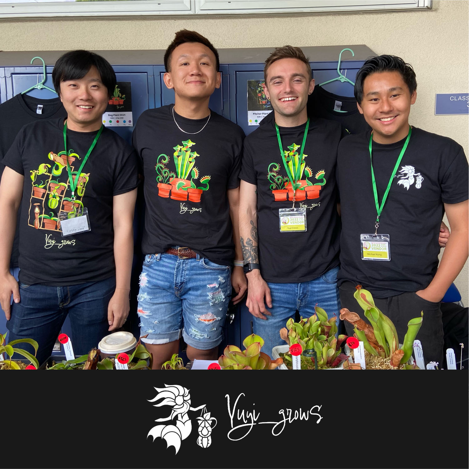 Four people stand together, smiling, wearing black "Kuii_grows" t-shirts with plant designs. They are in front of a wall with lockers and a display of small potted plants in front of them.